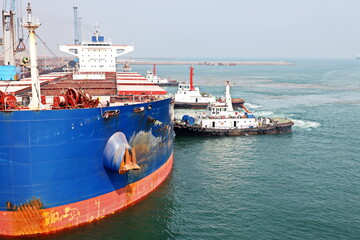 A large bulk carriers, tugboats at the port under cargo operations and underway.  Gopalpur, India, November, 2020.