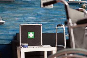 Hospital medical bag equipment standing on table in empty living room with nobody in it during healthcare therapy recovery. Social support nursing services at home. Rehabilitation assistance service