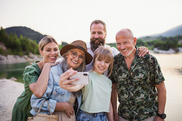 Happy multigeneration family on hiking trip on summer holiday, taking selfie.