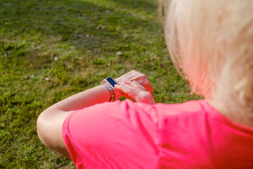 Sporty senior woman checking her smartwatch during training.