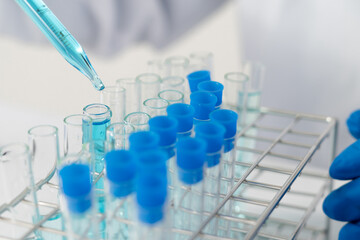 Biochemistry laboratory research, Scientist or medical in lab coat holding test tube with using reagent with drop of color liquid over glass equipment working at the laboratory.