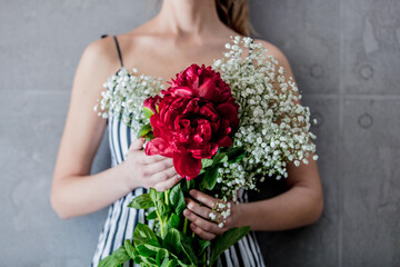 Female holding bouquet with Gypsophila paniculata and peonies