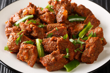 Tibs is an Ethiopian dish consisting of stir-fried meat and vegetables closeup in the plate on the table. Horizontal