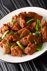 Tibs is a popular Ethiopian dish of sautéed beef flavored with niter kibbeh and berbere closeup in the plate on the table. Vertical