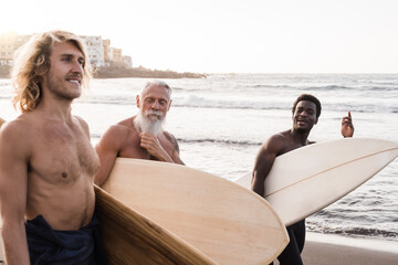 Diverse surfer friends holding surf boards after extreme water sport session with beach on...