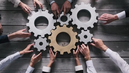 Teamwork business people concept. Different hands of men and women connect gears into working mechanism on wooden table background. - Powered by Adobe