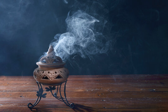 incense burning in an incense burner on the table,with dark background.Religion concept.