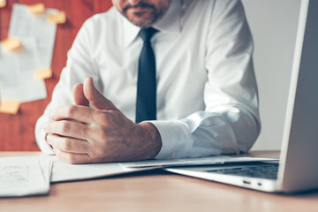 Bored businessman playing with thumbs of his hands in the office