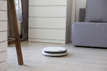 Smart House. Vacuum cleaner robot runs on wood floor in a living room