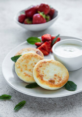 Cottage cheese pancakes, ricotta fritters on ceramic plate with  fresh strawberry.