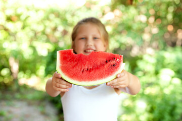 Cute child girl eats watermelon. Selective focus on pies of watermelon in hands