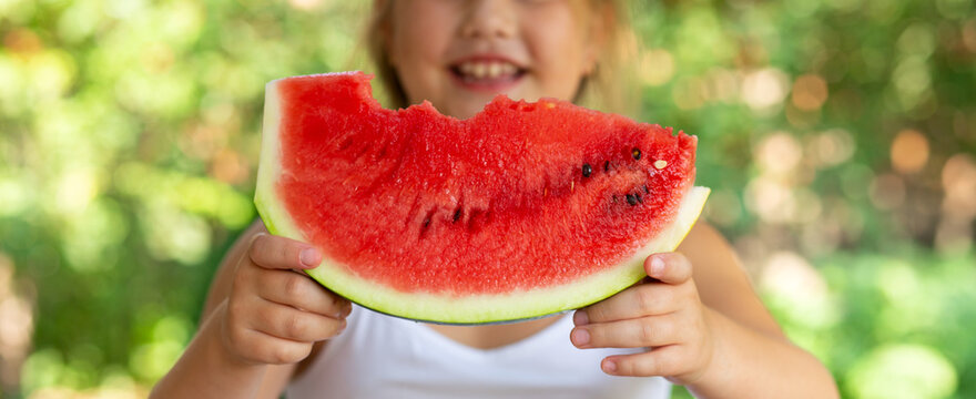Cute child girl eats watermelon. Selective focus on pies of watermelon in hands