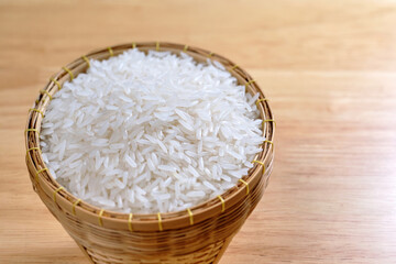raw Thai's jasmine rice in Thai's traditional style bamboo's bowl on wooden dinner table