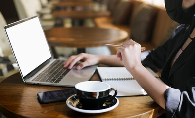 Focus on hand young asian businesswoman holding pen and wearing face mask using laptop working or meeting online