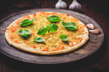 Pizza bread with garlic, cheese and basil on wooden background