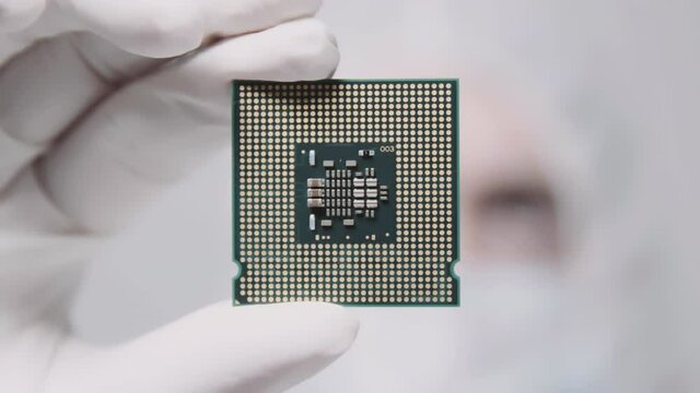 Engineer in Cleanroom suit holds CPU processor hand. Chip Fabrication laboratory