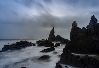 Beautiful Long exposure Image of the ocean waves hitting the big sharp rocks at the beach side of...
