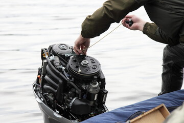 Boater hand start an outboard boat motor without the hood cap on the transom of the boat, emergency...