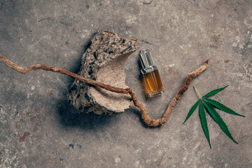 Glass bottle with CBD oil, THC tincture and hemp leaf on gray marble background. naturalness. CBD oil cosmetics.
