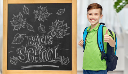 education, learning and people concept - happy smiling student boy with school bag over chalkboard with back to school lettering on background