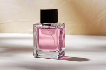beauty, perfumery and object concept - bottle of perfume on white surface with shadows