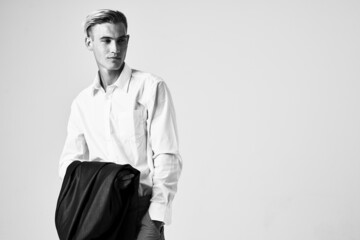 man in white shirt with jacket in hands cropped view light background