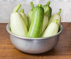 Raw zucchini and vegetable marrow in kitchen bowl on table