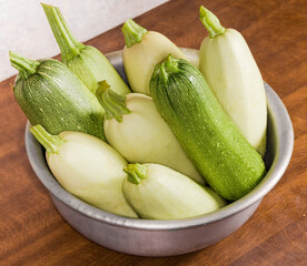 Raw zucchini and vegetable marrow in kitchen bowl, top view