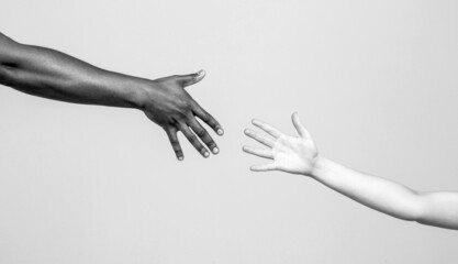 Black and white human hands. African and caucasian hands. Giving a helping hand to another. Helping...