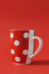 Red mug object with big white dots on vibrant color red background with copy space.