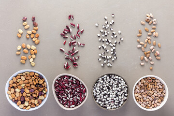 Different types of legumes in bowls and scattered in the background, Pinto beans, red and white...