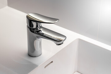 Stainless faucet on clean wash new basin sink in bathroom, concept of clear and healthy.