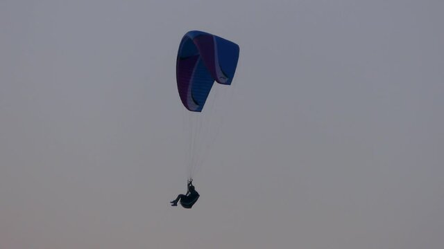 Man on a paraglider against the sunset sky.