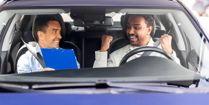 driver courses, exam and people concept - happy smiling indian man and driving school instructor with clipboard in car