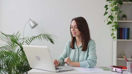 Fun young successful employee business woman in casual shirt sit work at white office desk conducting pleasant conversation talk speak on pc laptop isolated on light background indoors studio portrait