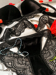 Set of women's black lace underwear bra and panties on a silk sheet subject photo close-up.