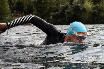 Athletic young man swimming at lake. Professional triathlon swimmer in action. Young man athlete practicing at open water