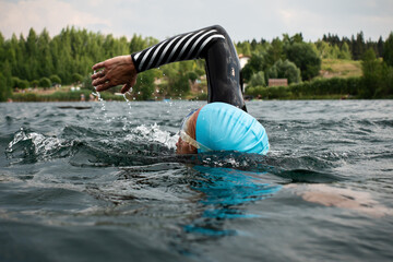 Athletic young man swimming at lake. Professional triathlon swimmer in action. Young man athlete...