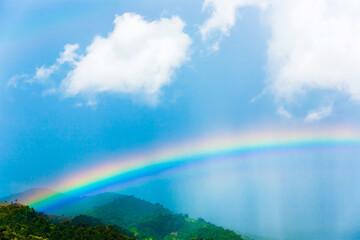 Colourful rainbow over green mountains.