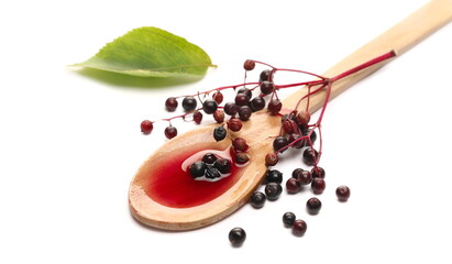 Squeezed elderberries juice, syrup in wooden spoon with elder berries and leaves isolated on white...
