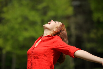 Happy woman screaming stretching arms in a forest