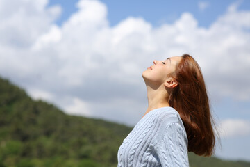 Woman breathing fresh air in the mountain sky