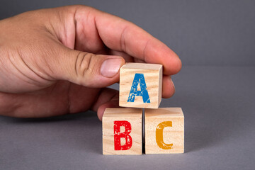 ABC alphabet wooden blocks and a man's hand on a gray background