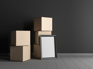 Vertical Black Wooden Frame Mockup standing near large cardboard boxes in empty interior with dark wall