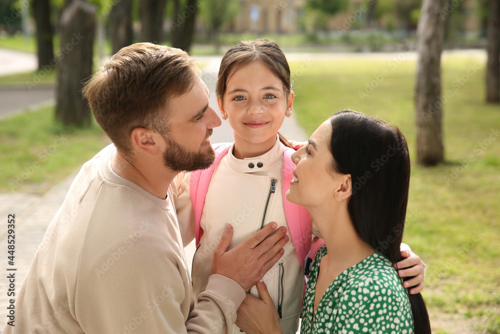 Wall mural Parents hugging their little daughter before school outdoors