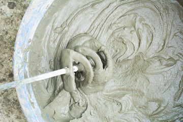 Construction technicians mixing concrete with electrical drill and mixer. Cement mix process