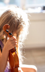 little violinist lit by the sun holds a violin before the concert