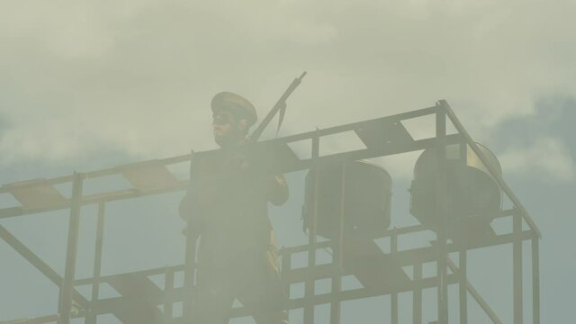 Security , guard , policeman stay in watch tower and looking around with not licensed decorative uniform and weapon . Silhouette of guard tower or prison tower with security man . Slow Motion . 