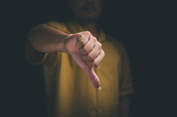 man hand showing thumb down sign gesture. Dislike or bad concept, dark tone.