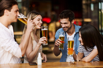 Group of young people in a summer cafe drinking beer